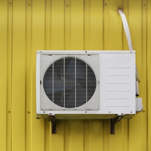 an air conditioner against a yellow metal wall