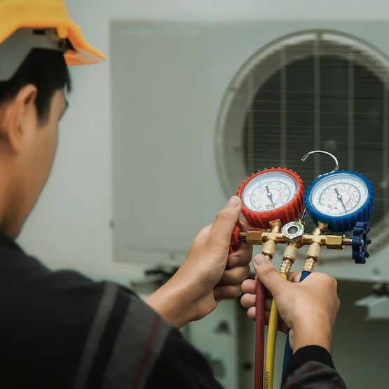 An HVAC contractor is checking the gauges during a repair.